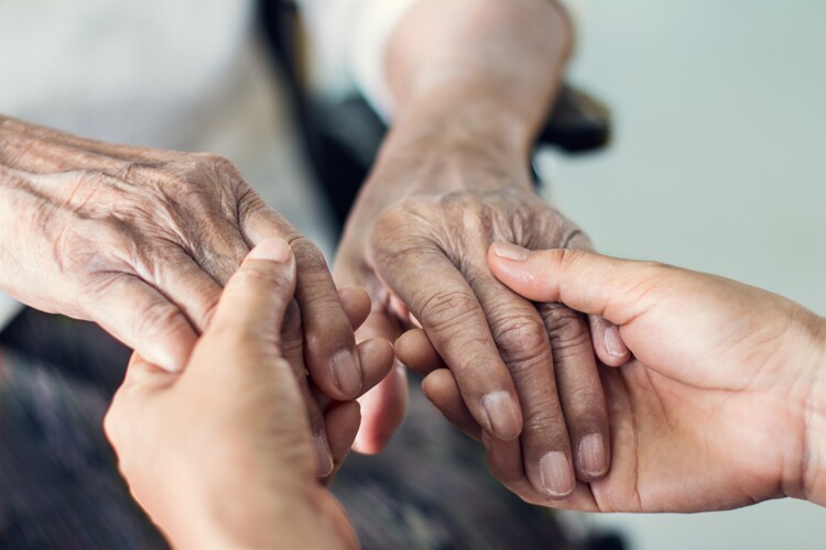 Elderly hands held in younger hands
