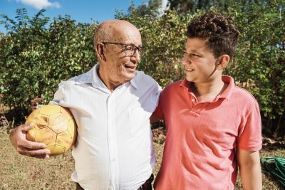 a boy walks and talks with his grandfather, who is holding a soccer ball