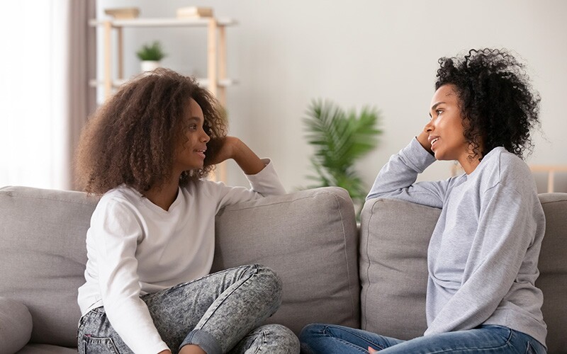 ソファで話し,積極的に耳を傾ける二人の女性。