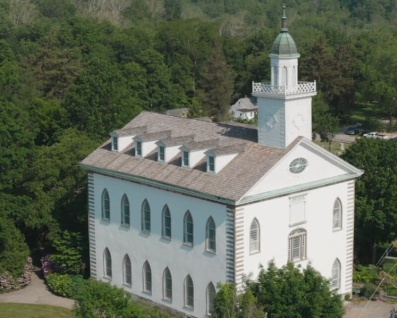 Bild einer weißen Kirche, die von Bäumen umgeben ist