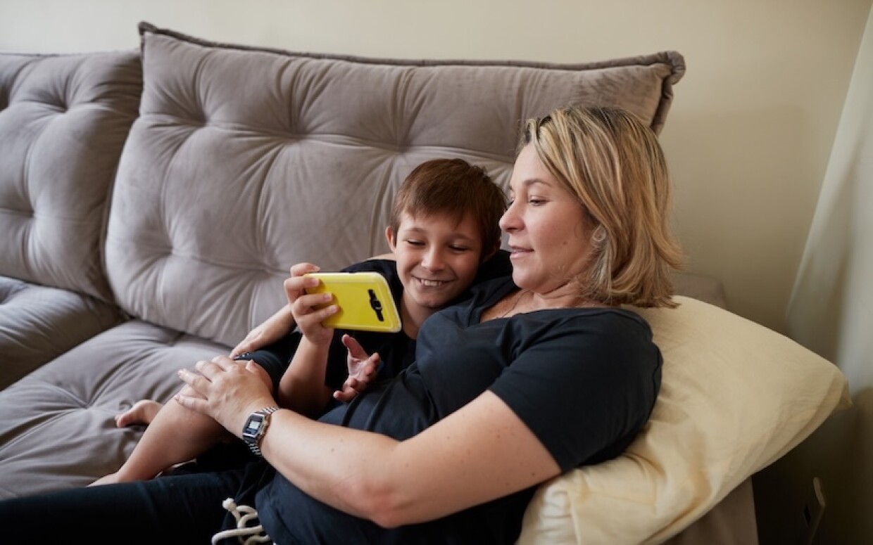 Eine Frau und ihr Sohn schauen auf ein Smartphone