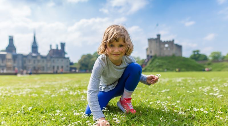 A young girl picks wildflowers in Cardiff, Wales.