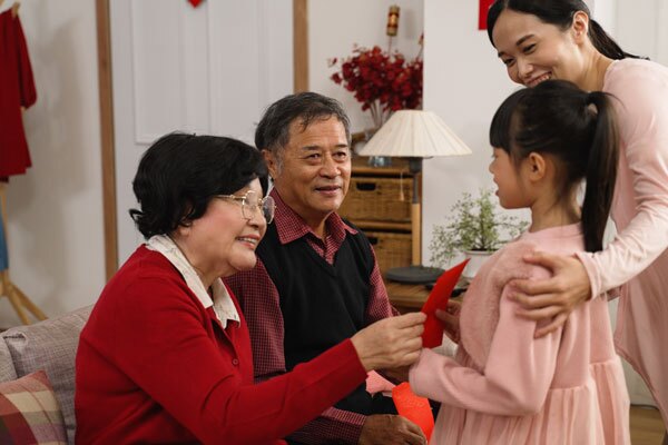 en liten flicka får ett rött kuvert eller hongbao av sina farföräldrar på det kinesiska nyåret