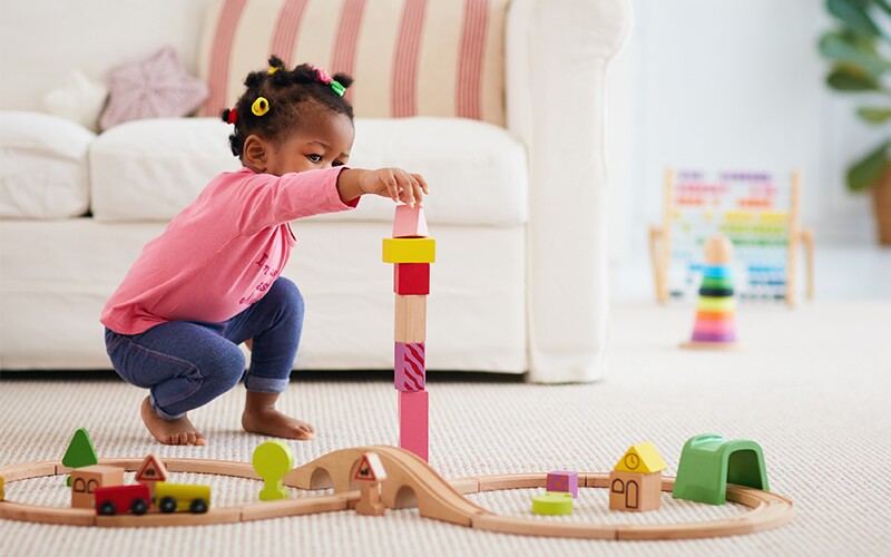 A toddler girl plays with blocks