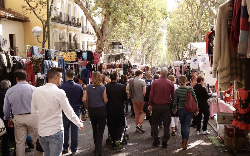 Una strada fiancheggiata da vestiti e bancarelle nel Rastro di Madrid