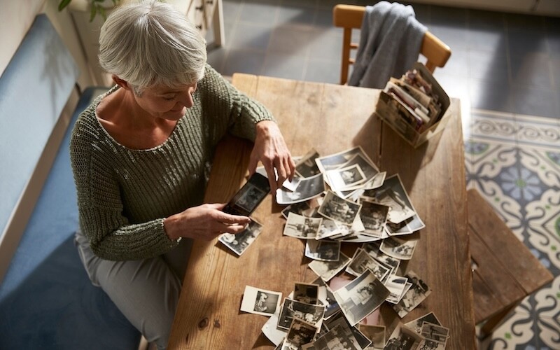An older woman taking photographs of old photos with a smartphone