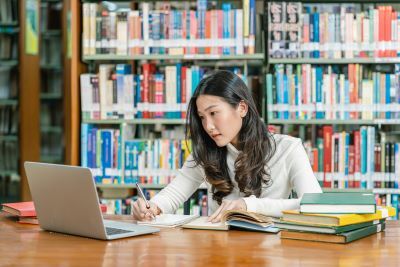 an Asian girl does research in a library