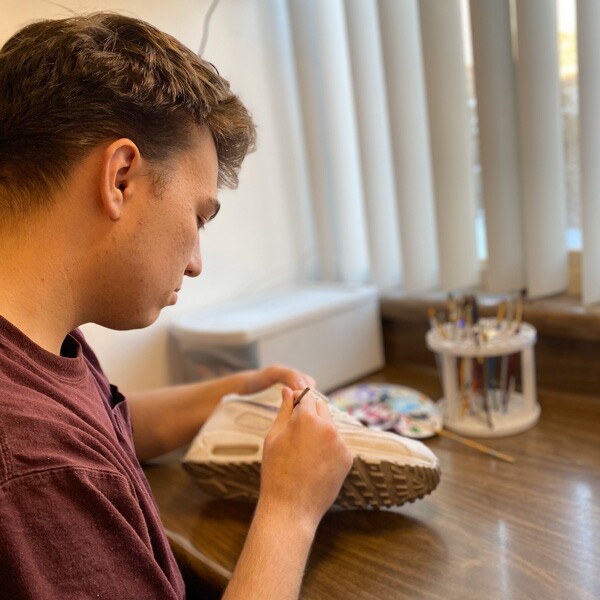 Carter Denos, painting a shoe.