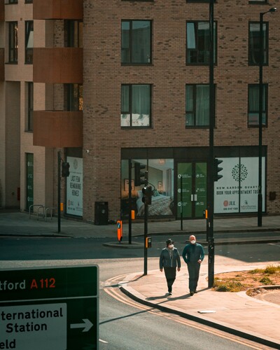 two people walk while wearing face coverings