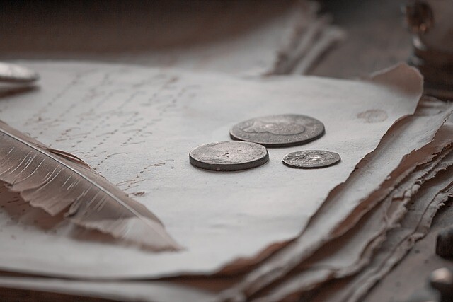 old coins sitting atop a stack of parchment