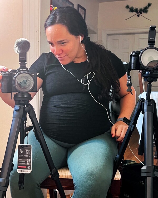 Nancy Borowick, enceinte, est assise derrière un appareil photo professionnel et se concentre tandis qu'elle prend une photo.