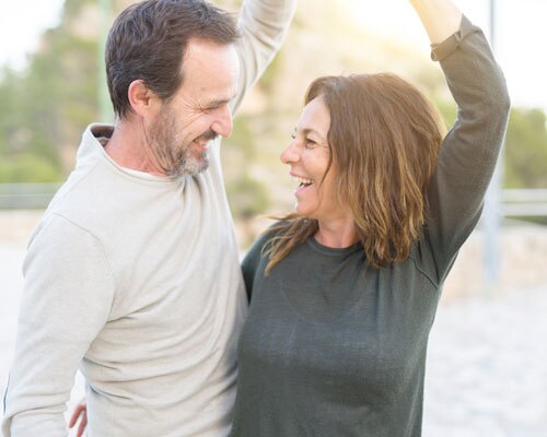 An older couple dance outside to the music and smile