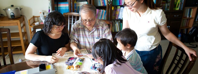 A family doing family history together, looking at their family chart and a family history pamphlet.