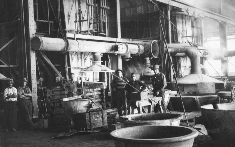 A black-and-white photograph of workers around the blast furnaces in the smelter at Mt. Isa Mines in Queensland, Australia, in 1932.