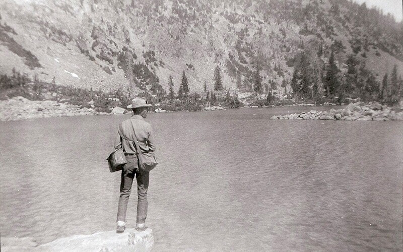 A vintage photo of a man fishing on a lake in Yellostone, the first national park.