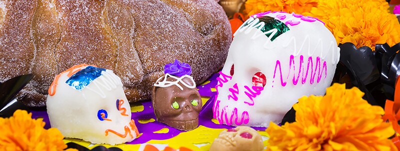 Цукрові черепи поряд із pan de muerto і чорнобривцями