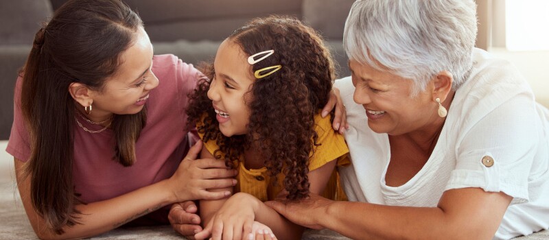 Une fille, une mère et une grand-mère latino-américaines sourient ensemble.