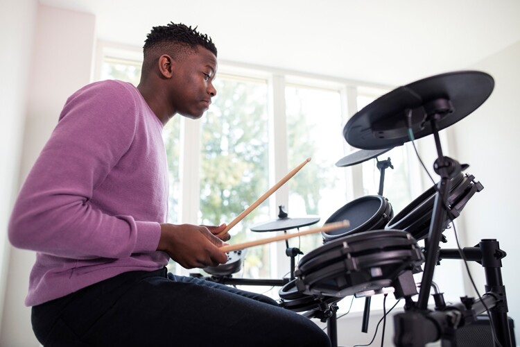 A man sits at his drumkit and writes a song