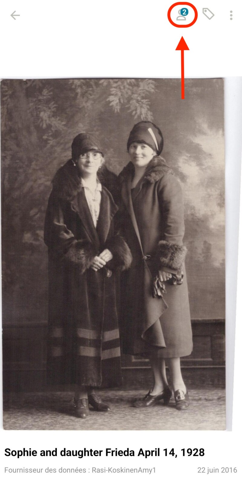 Une photo de deux femmes debout ensemble, comme on peut le voir dans le visualiseur de souvenirs de FamilySearch. Un ovale rouge entoure une icône en forme de personne dans le coin avec une flèche pointant vers elle.