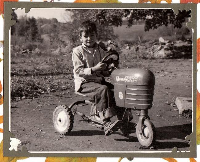 Et svart-hvitt-bilde av en gutt som kjører en liten traktor, før MyHeritage In Color har blitt brukt