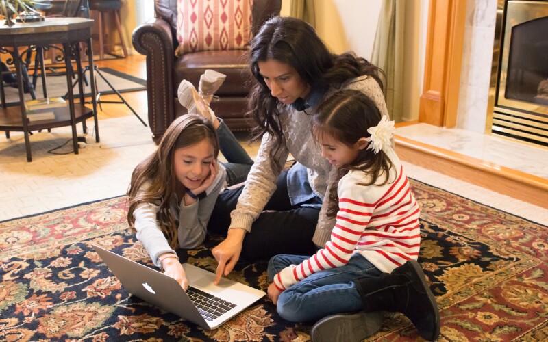 A mother doing family history on a laptop with her two daughters