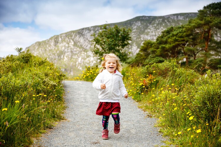 a little irish girl runs down a path.